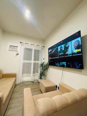 Una sala de estar con un televisor de pantalla plana montado en la pared que muestra varias opciones de películas.