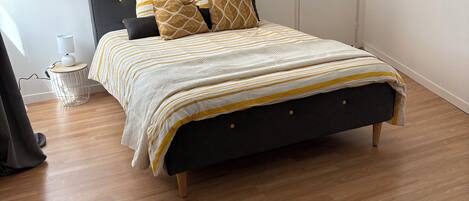 A bed with a dark headboard, a striped bedspread, and patterned pillows.