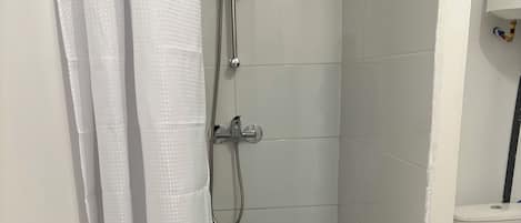 A shower area with a showerhead, a handheld shower, and a drain.