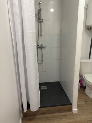 Zona de dutxa amb testoseta, plat de roba i desguàs.