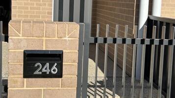 A brick building with a metal gate and a mailbox with the number 246.