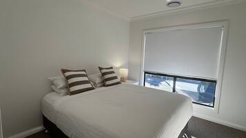 A hotel room with a large bed, a window with a view, and a ceiling light.