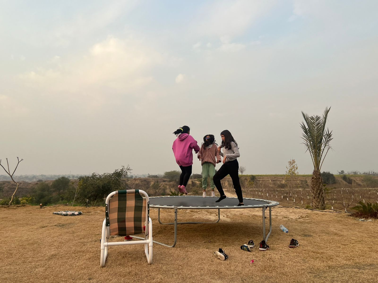Een trampoline in een open ruimte met een stoel en verspreide schoenen.
