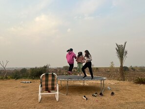 Een trampoline in een open ruimte met een stoel en verspreide schoenen.