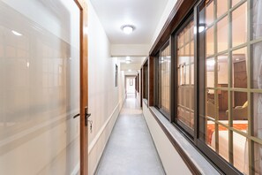 Un pasillo con una puerta de madera a la izquierda y una ventana a la derecha.