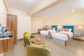 A hotel room with two beds, a desk, a chair, and a small table.