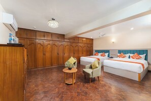 A hotel room with two beds, a wooden wardrobe, a small round table with a plant, and a ceiling fan. - Boudha Vilasa Hotel, Near Boudhanath Stupa (Kathmandu)