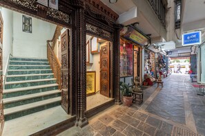 Una calle estrecha con una escalera que conduce a un edificio con puertas de madera ornamentadas y una recepción.
