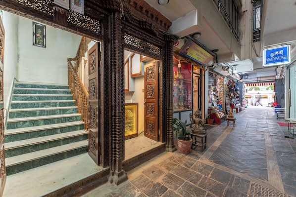 A narrow street with a staircase leading to a building with ornate wooden doors and a reception area.