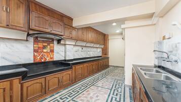 A kitchen with wooden cabinets, a marble backsplash, and a patterned floor.