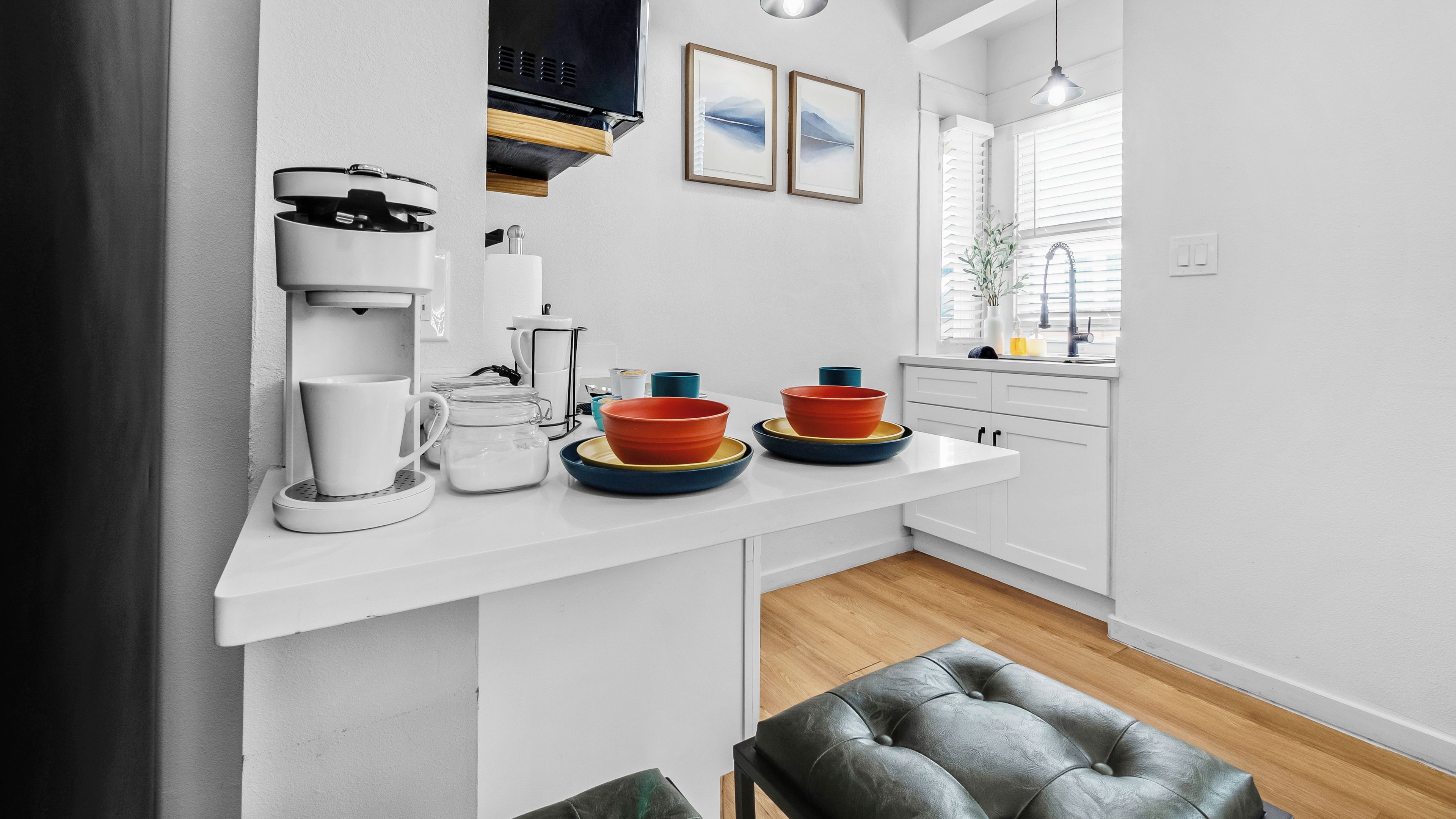 Eine moderne Küche mit weißen Schränken, einer Kaffeemaschine und einer Arbeitsplatte mit Schüsseln und Tassen.