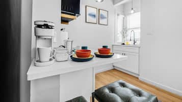 Eine moderne Küche mit weißen Schränken, einer Kaffeemaschine und einer Arbeitsplatte mit Schüsseln und Tassen.