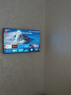 A flat-screen TV mounted on a wall displaying a Netflix interface with a snowy landscape background. - Very bright apartment, 5 min from the Twins, Casablanca (Casablanca)