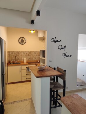 A modern kitchen with a wooden island, a clock, and a wall sign saying 'Home Sweet Home'. - Very bright apartment, 5 min from the Twins, Casablanca (Casablanca)