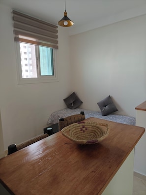 A room with a bed, a window with blinds, a hanging light fixture, and a wooden table with a woven basket. - Very bright apartment, 5 min from the Twins, Casablanca (Casablanca)
