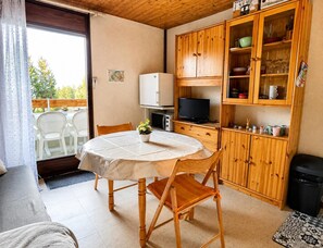 A compact kitchen with wooden cabinets, a dining table, and a television. - Alpine Ski Apartment in Tignes for 4 (Morillon)