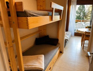 Ein Stockbett mit einer unteren Liege und einem Tisch mit Stühlen im Zimmer.