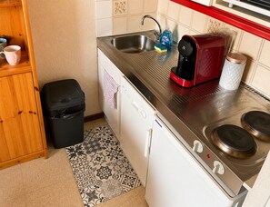 Eine kleine Küche mit Spüle, Kaffeemaschine, Toaster und Geschirrspüler.