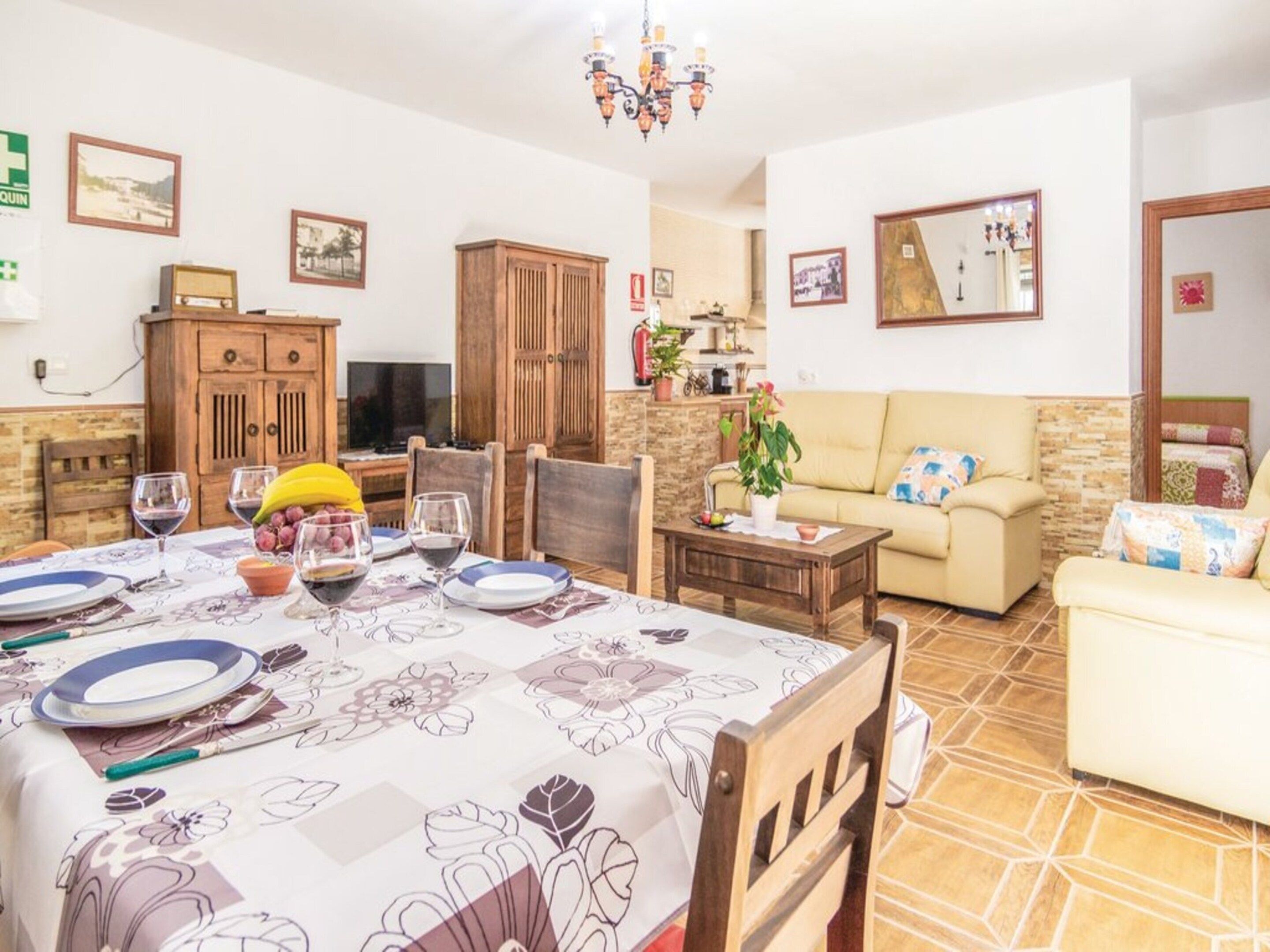 Zona de menjador amb taula preparada per a quatre, un sofà i una televisió al fons.