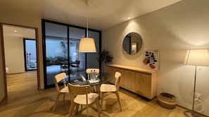 A modern dining area with a glass table, wooden chairs, a hanging lamp, a wooden cabinet, and a mirror on the wall. - w Upscale 2BR With Private Terrace in Roma Norte (Mexico City)