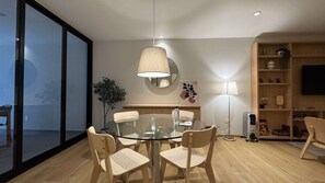 A modern dining area with a glass table and wooden chairs, a round mirror, and a floor lamp. - w Upscale 2BR With Private Terrace in Roma Norte (Mexico City)