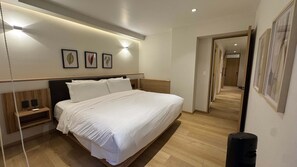 Ein Hotelzimmer mit einem großen Bett, Nachttischen, einer Wandleuchte und gerahmten Pflanzenbildern.
