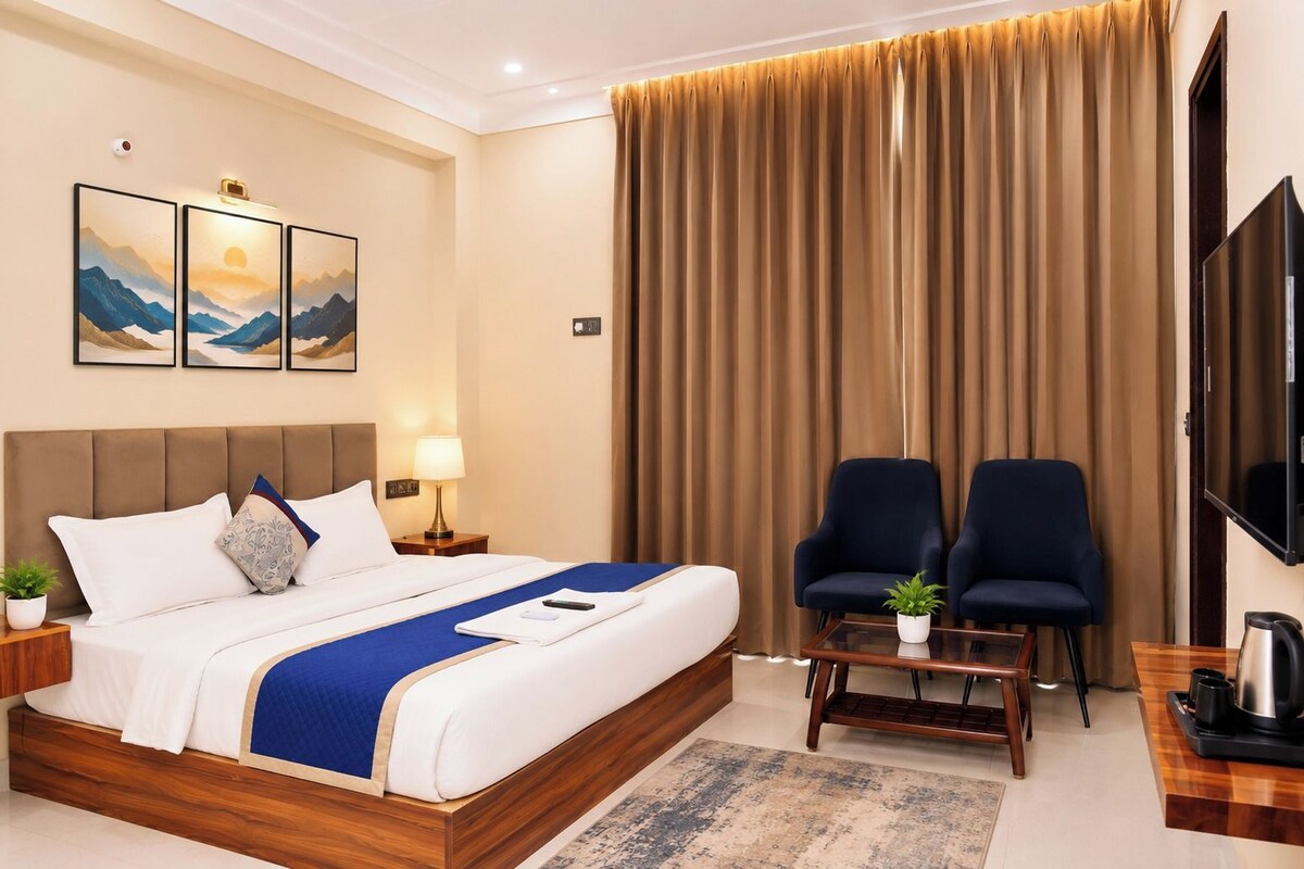 Una habitación de hotel con una cama, dos sillones, un televisor y una cafetera.