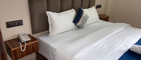 A hotel room with a bed, a bedside telephone, and a nightstand.