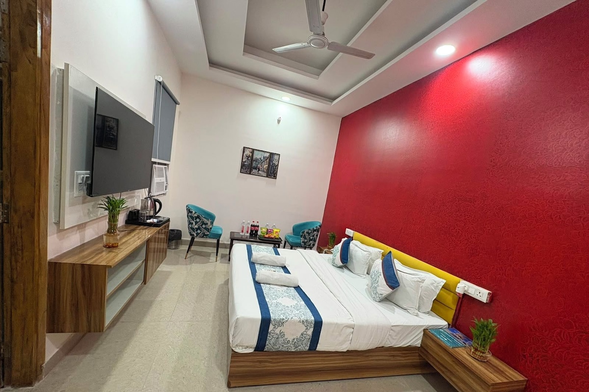 A bedroom with a bed, a TV, a desk, and a chair.