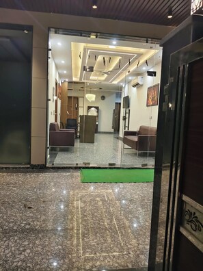 A hotel lobby with a reception desk, seating area, and a chandelier. - Dr Hotel Grand Plaza (Greater Noida)
