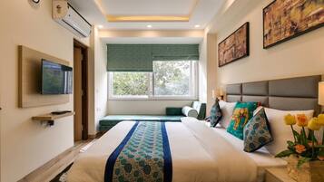 Una habitación de hotel con una cama, televisión, ventana con vistas y obras de arte en las paredes.