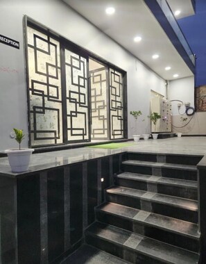Un área de recepción de diseño moderno, con mostrador de recepción, un conjunto de escaleras y una pared con diseño geométrico.