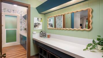 Une salle de bain moderne avec un comptoir blanc, un grand miroir et un ventilateur.