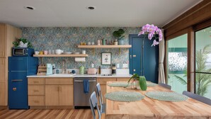 Eine moderne Küche mit Holzschränken, einer eingebauten Mikrowelle und einem Essbereich mit Holztisch und Stühlen.