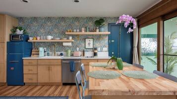Une cuisine moderne avec des meubles en bois, un four à micro-ondes encastré et un coin repas comprenant une table et des chaises en bois.
