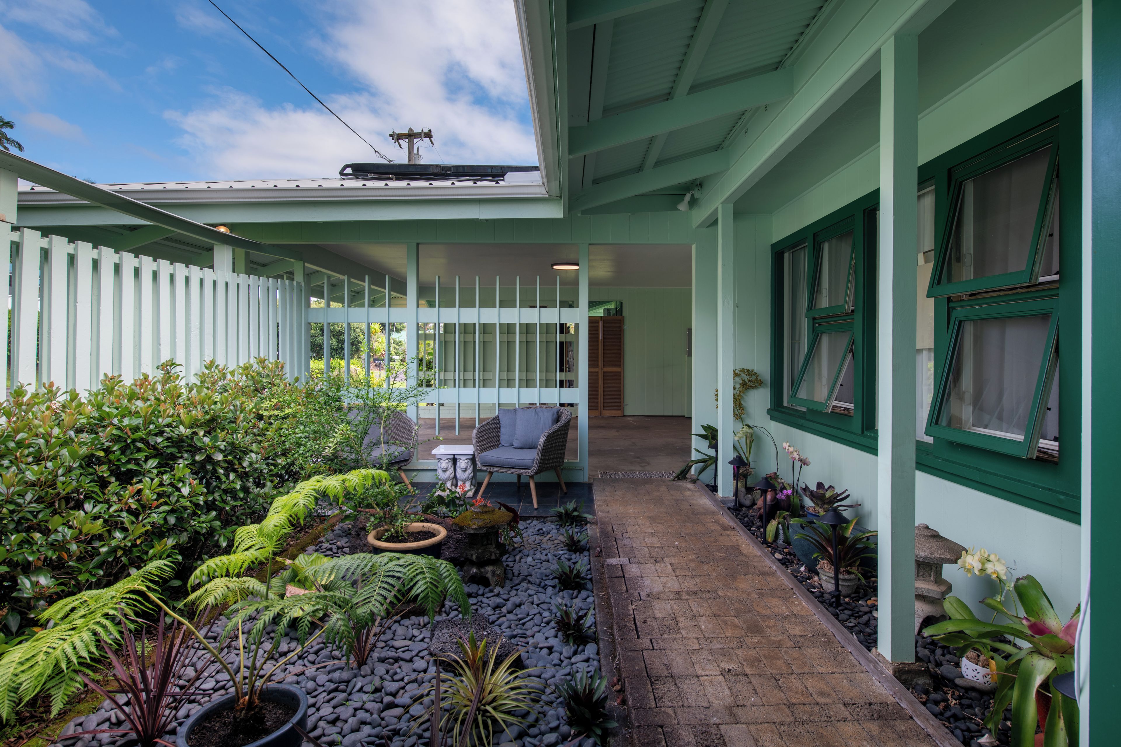 Un espace extérieur abrité, doté d’un chemin en briques, de plantes en pot et de mobilier de jardin.