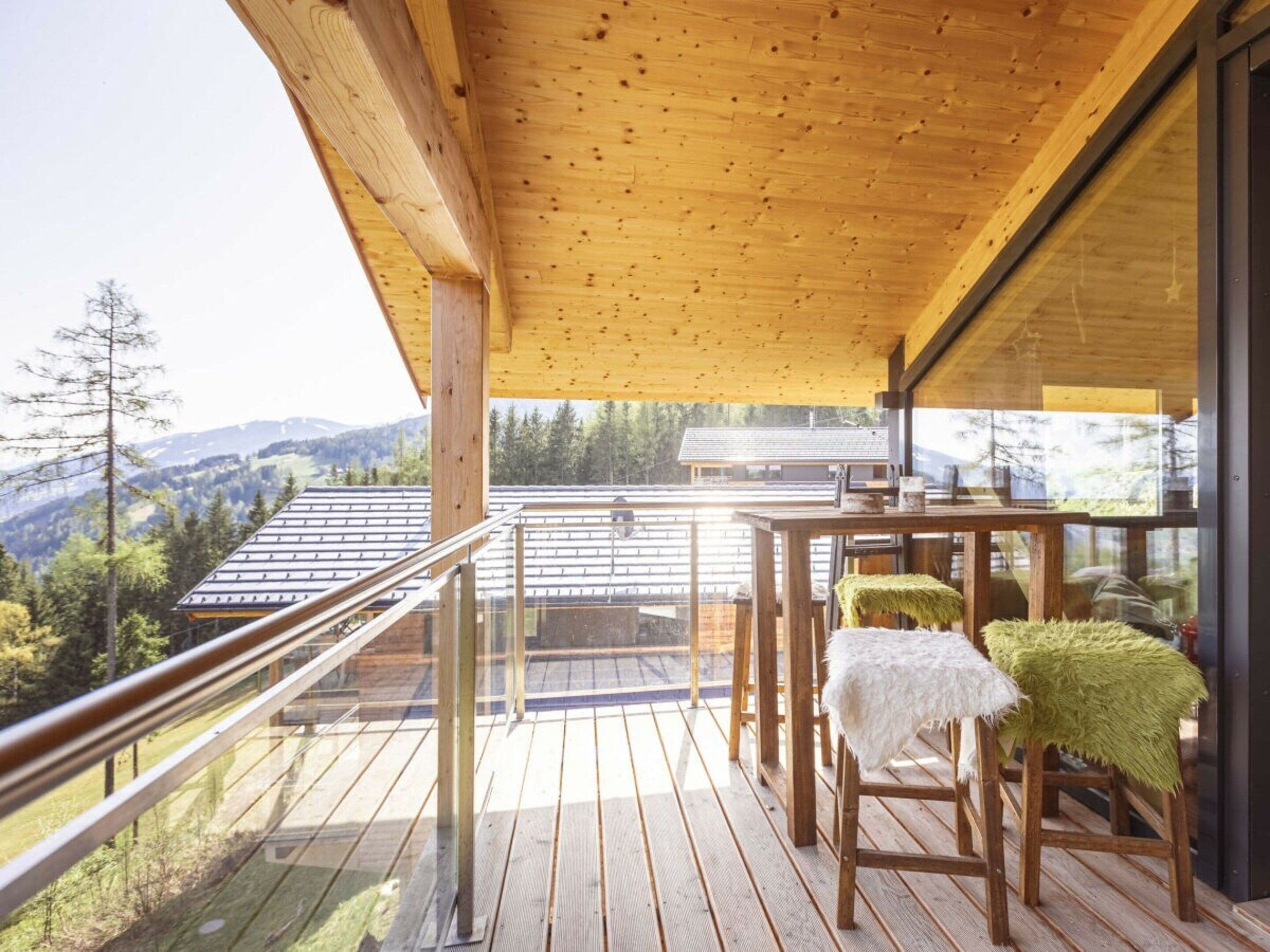A wooden deck with a glass balustrade overlooking a mountainous landscape.