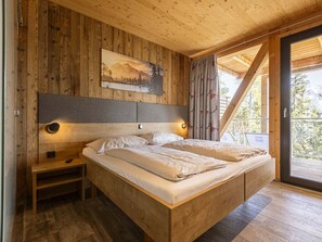 A wooden bedroom with a bed, nightstands, and a painting on the wall. - Premium Chalet #13 With Sauna & Swim Spa (Schladming)