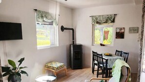 A room with a sofa, a small table, a chair, a TV mounted on the wall, and a fireplace with a chimney.