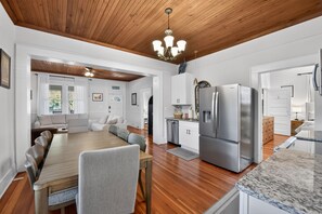 A modern kitchen with a wooden ceiling, stainless steel appliances, and a dining area with a wooden table and chairs. - QCA House | 1 Mile to Bryant-Denny Stadium! (Tuscaloosa)