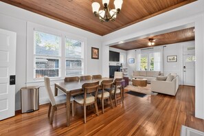 A spacious living area with a dining table and chairs, a sofa, and a ceiling fan. - QCA House | 1 Mile to Bryant-Denny Stadium! (Tuscaloosa)