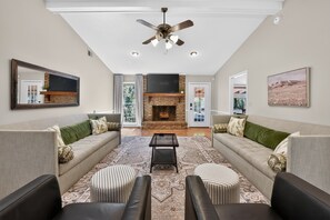 A spacious living room with a fireplace, two sofas, a coffee table, and a ceiling fan.
