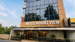 Un moderno edificio de hotel con una amplia fachada de vidrio y el nombre 'HOTEL MOUNT VIEW' bien visible.
