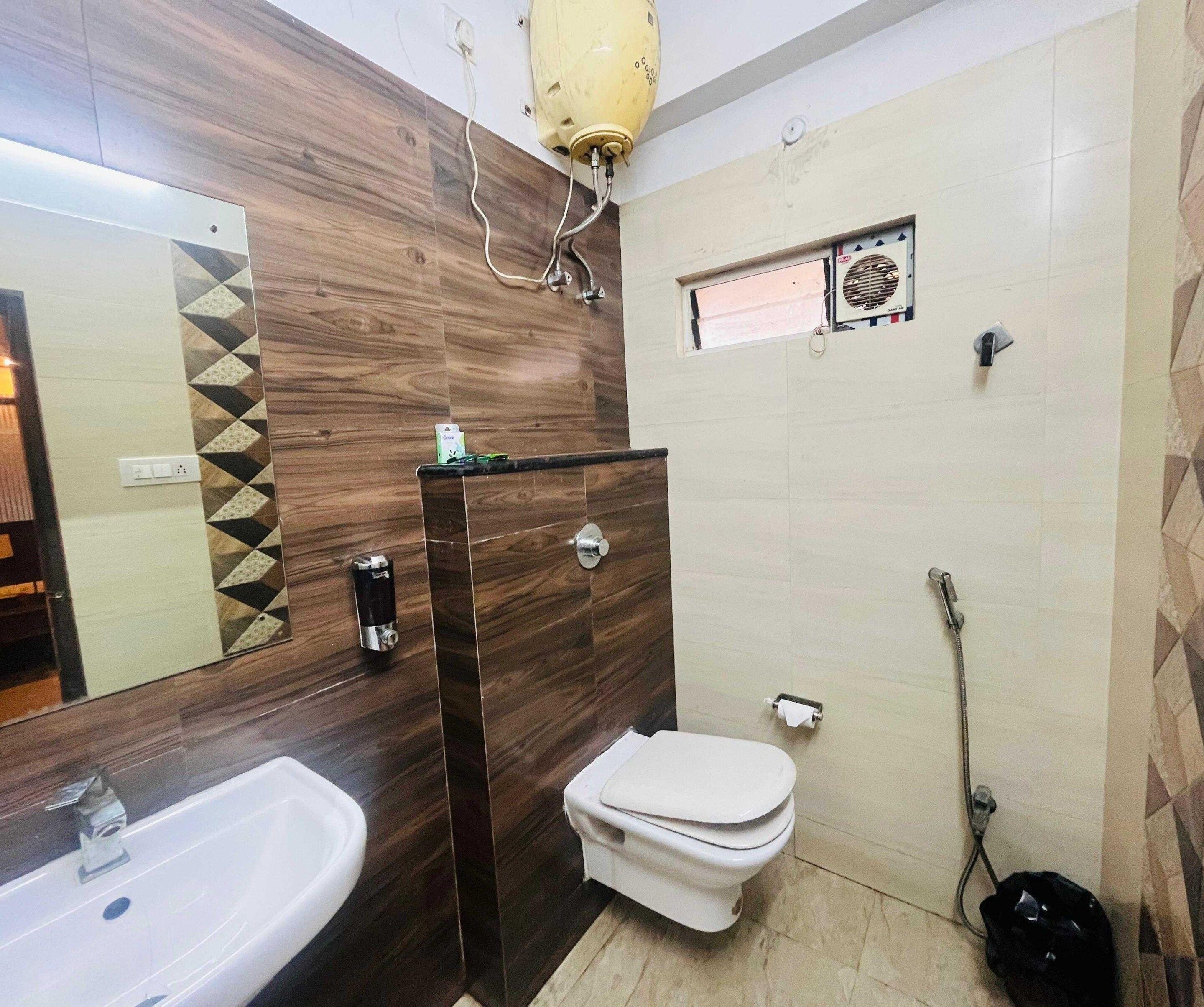 A bathroom with a wooden vanity, a white sink, a toilet, and a shower area.