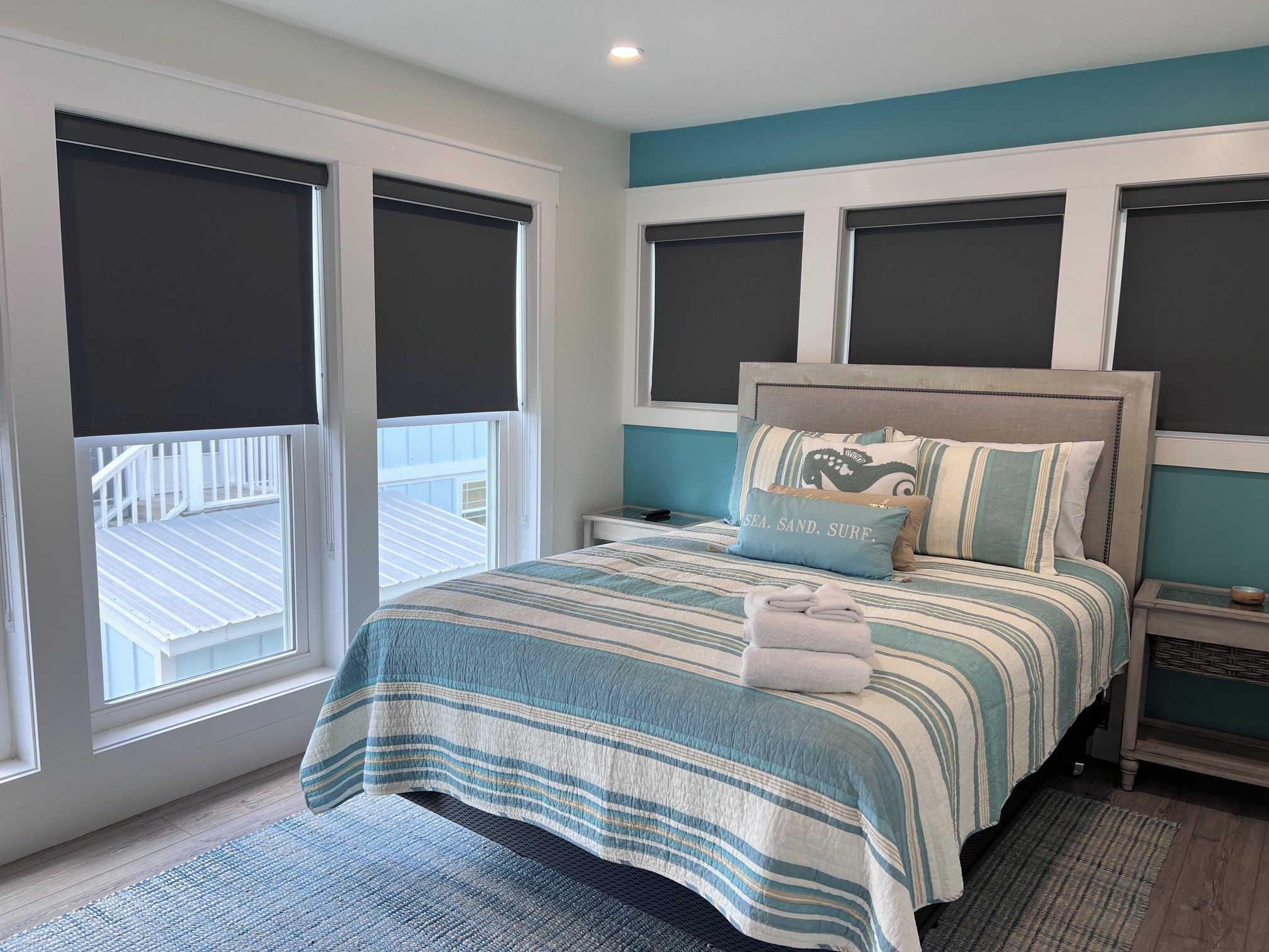 A bedroom with a bed, nightstands, a headboard, and a view of a balcony.