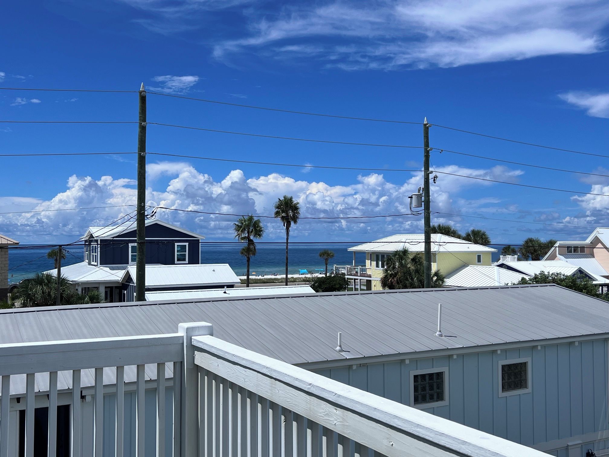Un quartier résidentiel situé sur la côte, avec des maisons, un ciel dégagé et une vue sur l’océan.