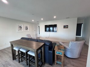 A modern living room with a dining area, a sofa set, a TV mounted on the wall, and artwork on the walls. - Luxury Gulf-View Home with Private Pool (Mexico Beach)