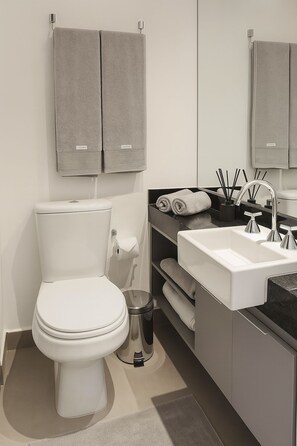 A modern bathroom with a toilet, sink, and towel storage. - Complete Studio Apartment in Jardins | Oscar Freire (São Paulo)