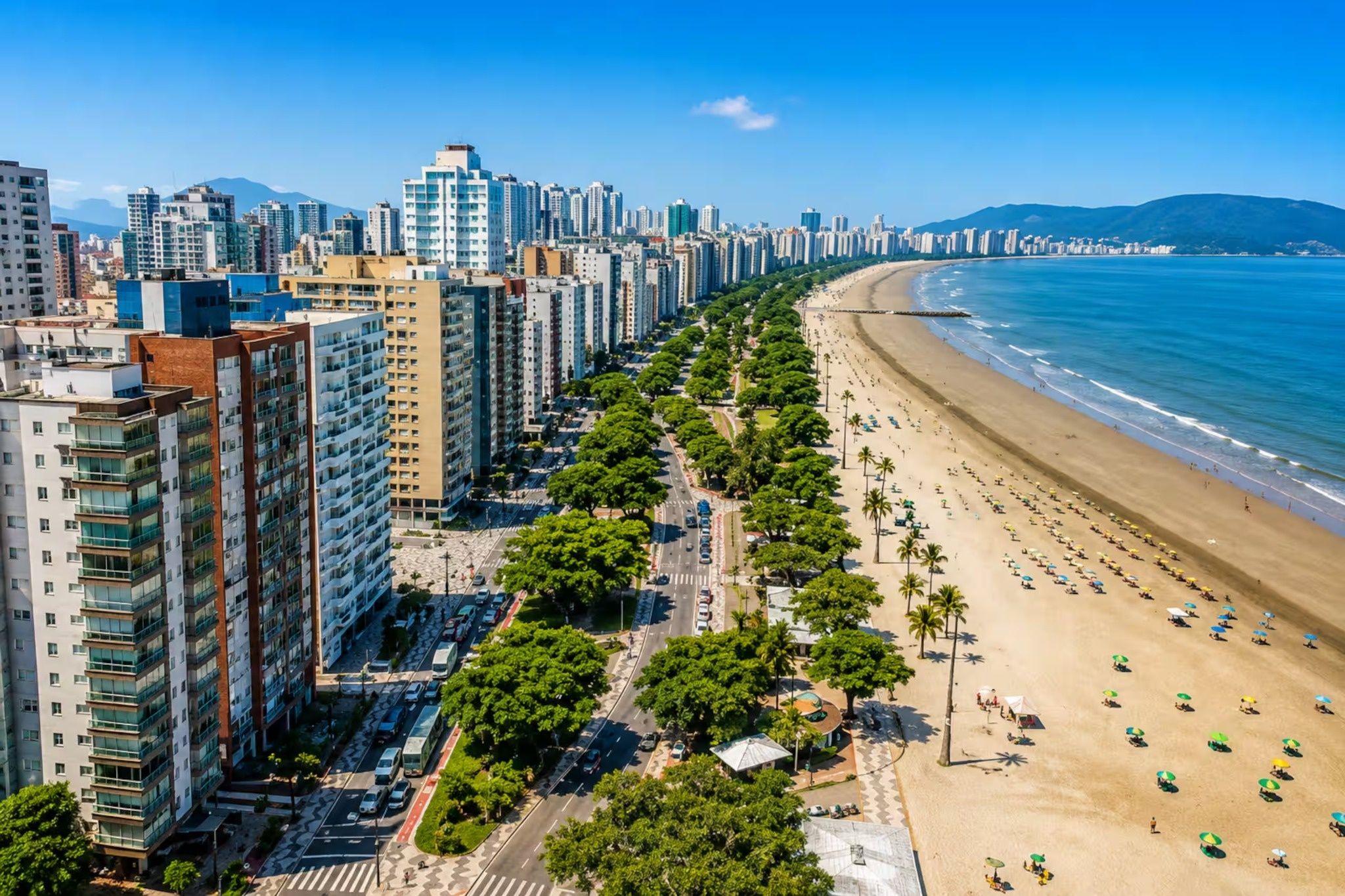 Un paysage urbain côtier avec de hauts immeubles, une vaste plage et un ciel bleu dégagé.