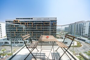 Eine Dachterrasse mit Holztisch und -bänken, mit Blick auf eine Stadtlandschaft mit modernen Gebäuden.